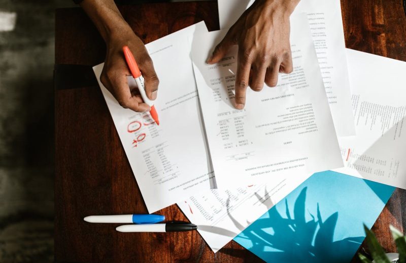 Haende markieren Finanzdokumente auf Schreibtisch